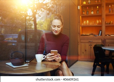 Portrait of young businesswoman use mobile phone while sitting in comfortable coffee shop during work break, charming happy female reading fashion news on cell telephone during breakfast in restaurant - Powered by Shutterstock