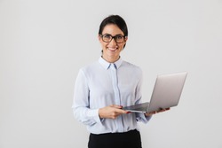 Portrait Of Young Businesswoman Wearing Eyeglasses Holding Silver Laptop In The Office Isolated Over White Background