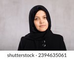 Portrait of young calm woman in hijab posing against background of studio