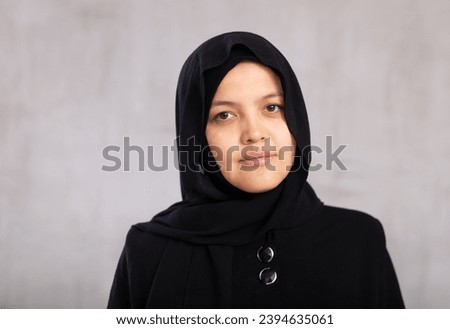 Portrait of young calm woman in hijab posing against background of studio