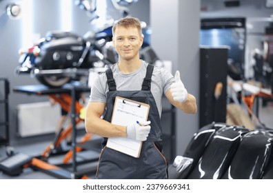 Portrait of young car mechanic holding clipboard and thumb up in car service. Recommendations for high-quality maintenance of cars and motorcycles concept - Powered by Shutterstock