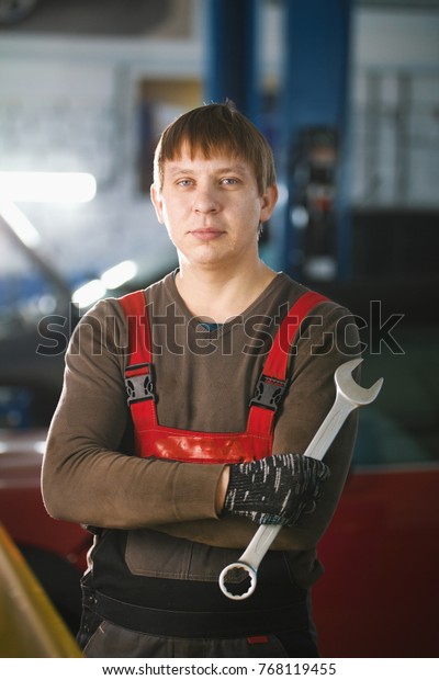 Portrait of a\
young car mechanic in a car\
workshop