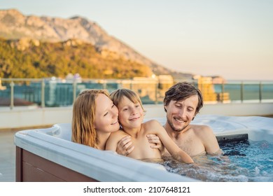 Portrait Of Young Carefree Happy Smiling Happy Family Relaxing At Hot Tub During Enjoying Happy Traveling Moment Vacation. Life Against The Background Of Green Big Mountains