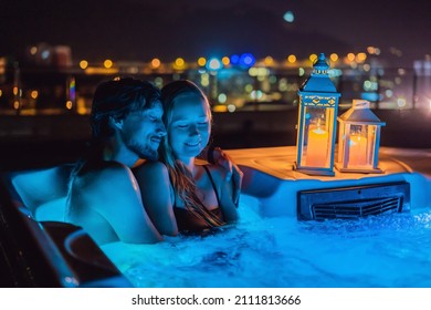 Portrait of young carefree happy smiling couple relaxing at hot tub during enjoying happy traveling moment vacation life against the background of green big mountains at night - Powered by Shutterstock