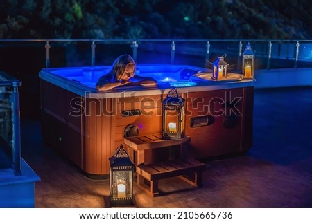 Portrait of young carefree happy smiling woman relaxing at hot tub at night during enjoying happy traveling moment vacation. Life against the background of green big mountains