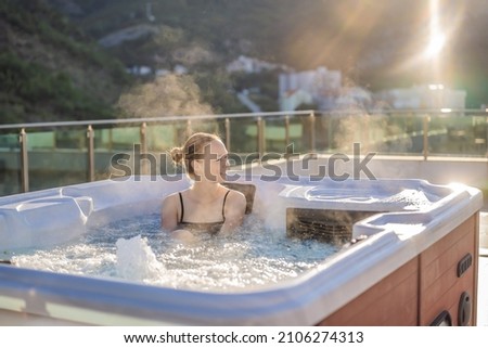 Portrait of young carefree happy smiling woman relaxing at hot tub during enjoying happy traveling moment vacation life against the background of green big mountains