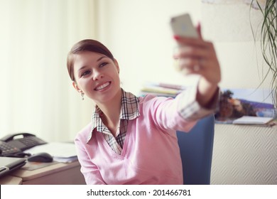 Portrait Of Young Caucasian Business Woman In Pink Vest At Her Office Doing Selfie On The Phone.