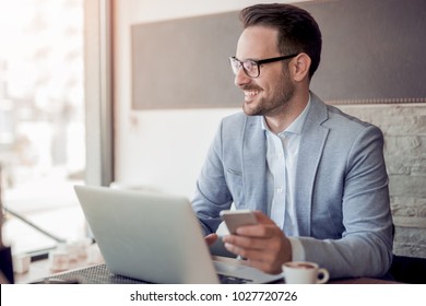 Portrait of young caucasian businessman in casual shirt and glasses using laptop computer at workplace. - Powered by Shutterstock