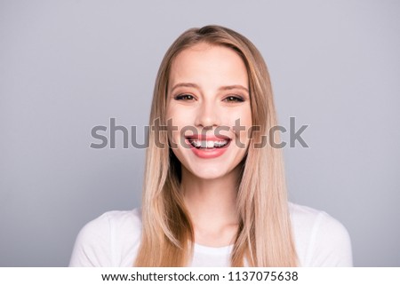 Portrait of young caucasian, charming, attractive smiling girl wearing casual white t-shirt. Isolated over grey background