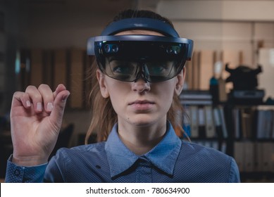 Portrait of young Caucasian female using augmented reality holographic hololens in modern office