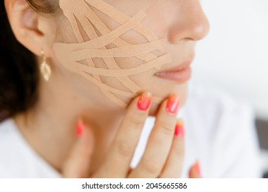 Portrait Of A Young Caucasian Girl In A White Coat With Tapes On Her Face. She Covers Her Face With Duct Tape. A Young Woman With Ribbons On Her Face. An Aesthetic Patch For The Face. A Patch To Maint