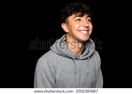 Similar – Portrait of a smiling Caucasian man in his 20s wearing a sweatshirt against a dark background.