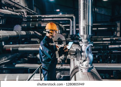 Portrait of young Caucasian man dressed in work wear using tablet while standing in heating plant. - Powered by Shutterstock