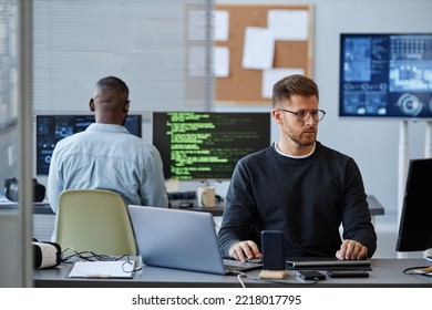 Portrait of young Caucasian man using computer while programming software in office, copy space - Powered by Shutterstock