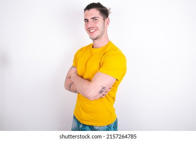Portrait of Young caucasian man wearing yellow t-shirt over white background standing with folded arms and smiling - Shutterstock ID 2157264785