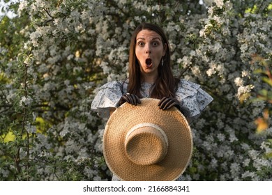Portrait of young caucasian shocked afraid woman looking with staring eyes, having wide open mouth. Her hands in black lace gloves hold a straw hat. Vacation concept. Seasonal allergy. Advertisement. 