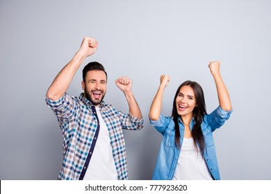 Portrait of young caucasian, sweet, foolish, attractive, lovely, cute, crazy, successful partners celebrating victory with raised fists, screaming, shouting over grey background