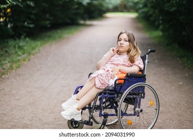 Portrait of young caucasian woman with disability in stylish summer dress looking at camera with green bushes on background. Time spending in fresh air. Lifestyles of wheelchair user. - Shutterstock ID 2094031990