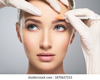 Portrait of young Caucasian woman getting cosmetic injection of botox  in forehead. Beautiful woman gets botox  injection in her face.