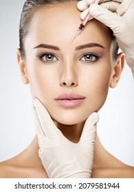 Portrait of young Caucasian woman getting botox cosmetic injection in forehead. Beautiful woman gets botox injection in her face. - Shutterstock ID 2079581944
