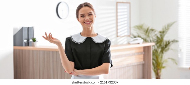 Portrait of young chambermaid near reception in hotel. Banner design