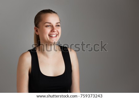 Portrait of young cheerful beautiful girl. With happy and relaxed face expression Smiling with teeth, looking at camera. Over grey background. Copy space.