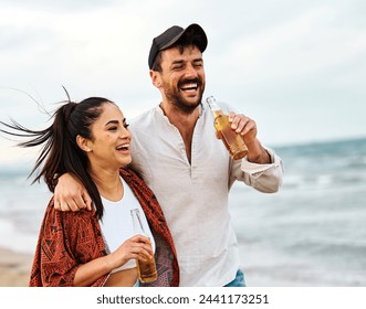 Portrait of a young cheerful couple  having fun walking and drinking beer at the party on the beach looking happy, Enjoying youth and freedom concept - Powered by Shutterstock