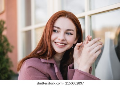 Portrait Of Young Cheerful Woman In Coat Looking Away Outside