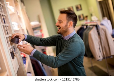 Portrait of a young cheerfull man looking at clothes to buy at shop - Shutterstock ID 1215145786