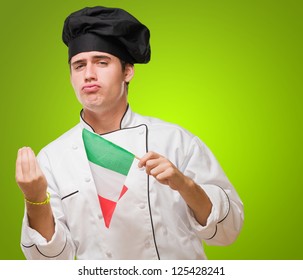 Portrait Of A Young Chef Holding Italian Flag against a green background