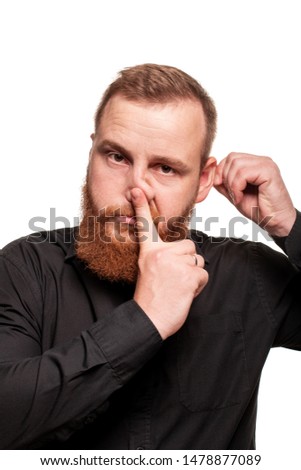 Portrait of a young, chubby, redheaded man in a black shirt making faces at the camera, isolated on a white background