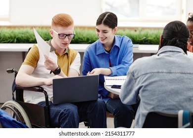 Portrait of young college student in wheelchair using laptop while participating in group discussion with friends, copy space - Powered by Shutterstock