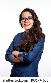  Portrait Of A Young Confident Woman With Long Wavy Hair And Glasses In Denim Shirt Smiling With Arms Crossed. Isolated On White