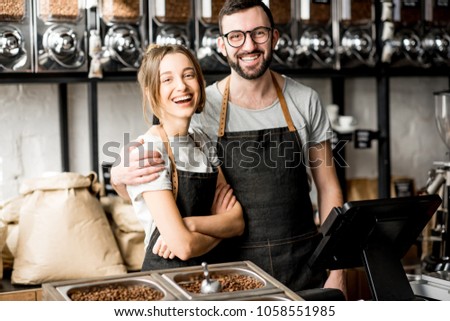 Portrait of a young couple of baristas standing together at the counter of the coffee store