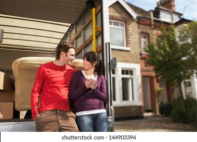 Portrait of young couple in front of new home with sold sign