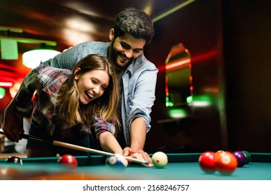 Portrait of young couple having fun playing billiard together.