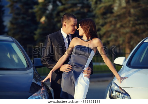 portrait\
of a young couple on a date standing near\
cars