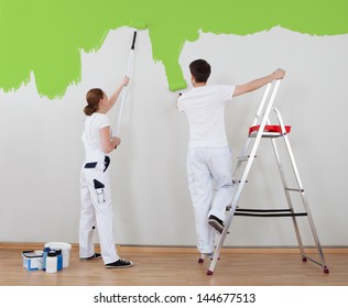 Portrait Of Young Couple Painting Wall Together