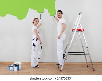 Portrait Of Young Couple Painting Wall Together