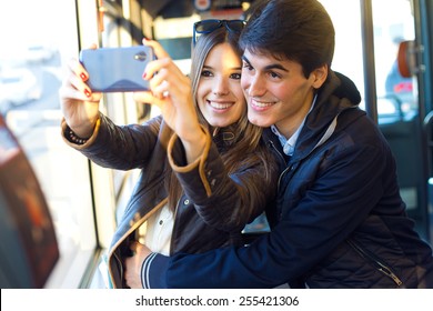 Portrait of young couple taking selfies with smartphone at bus. - Powered by Shutterstock