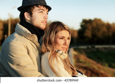 Portrait of a young couple in  warm clothes watching sunset.