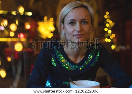 Portrait of a young cozy with cup of coffee, cookie and Christmas lights and pine branch