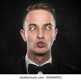 Portrait of a young cross-eyed businessman with funny face over dark background.