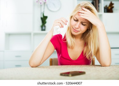 Portrait of young crying girl waiting for call sitting indoors