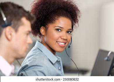 Portrait Of Young Customer Service Representative With Male Colleague Working In Office