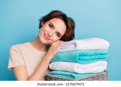 Portrait Of Young Cute Kind Woman Working Around House Leaning On Pile Of Washed Towels Isolated On Blue Color Background