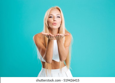 Portrait of a young cute woman blowing kiss at camera isolated on the blue background - Powered by Shutterstock