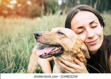 Portrait Of A Young Cute Woman With Her Beautiful Dog Lying Outdoors In Park. Shelter Dog And Volunteer Concepts.