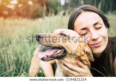 Portrait of a young cute woman with her beautiful dog lying outdoors in park. Shelter dog and volunteer concepts.