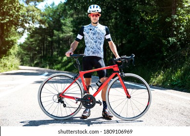 Portrait Of Young Cyclist With His Bike On The Road. Sport Concept